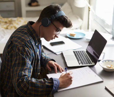 Pictured is boy studying with music.